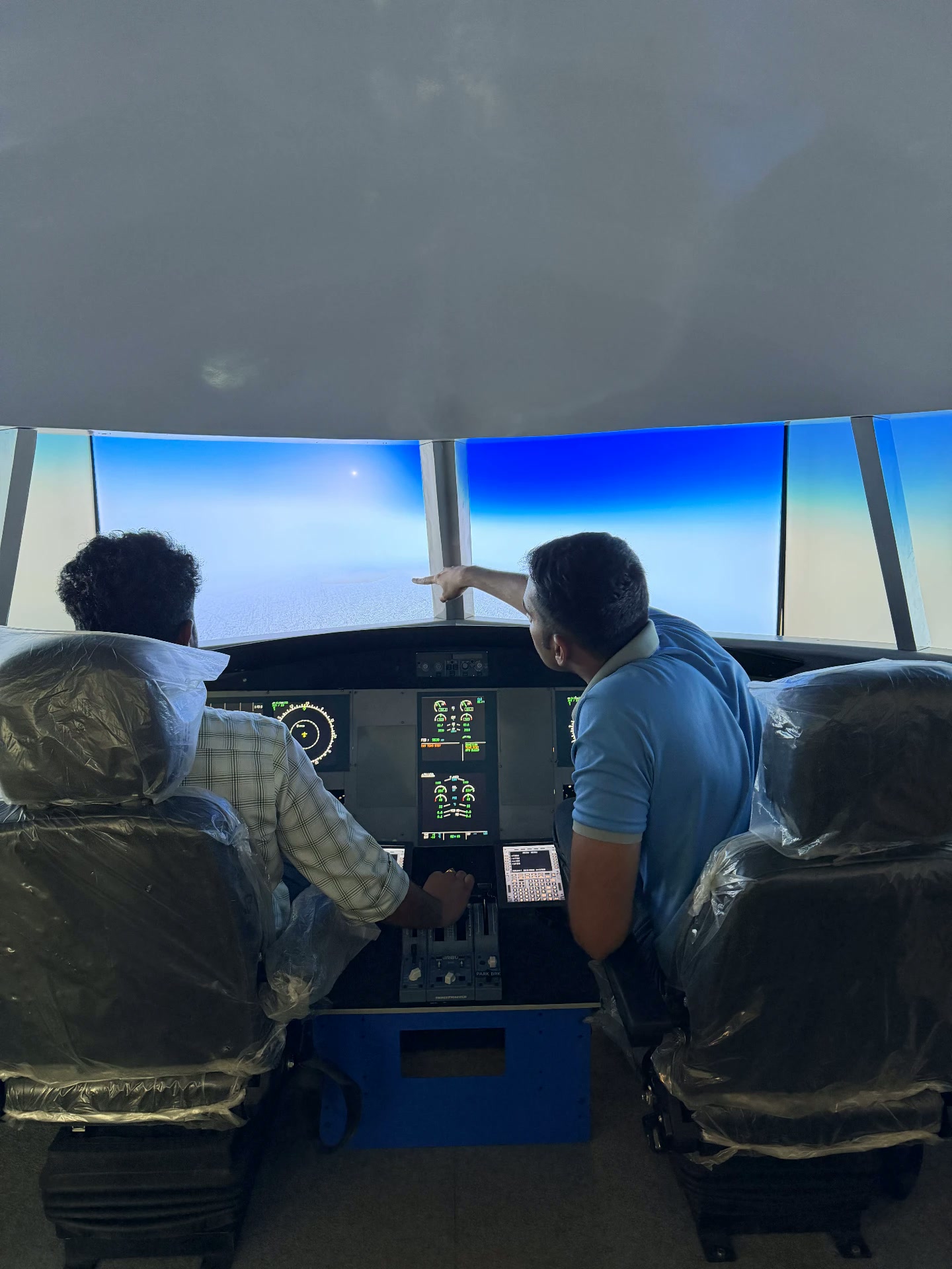 A guest at the A320 simulator controls while the instructor points out the flight path on the displays