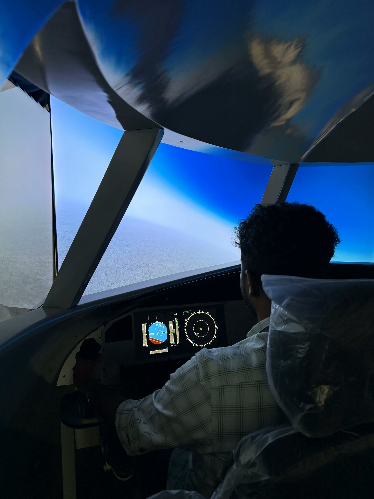Guest flying the A320 simulator with hands on the sidestick and the flight displays ahead