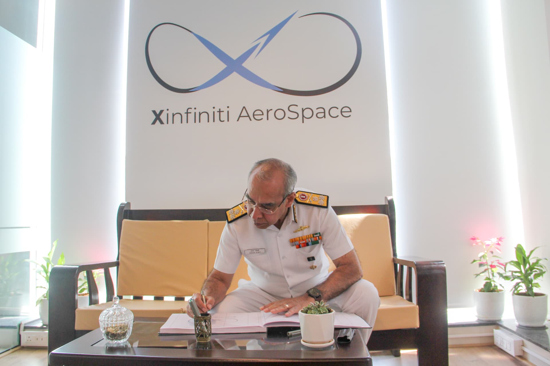 Rear Admiral signing the visitor book at Xinfiniti AeroSpace